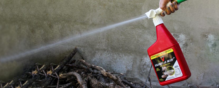 Snake-A-Way Hose End Snake Repellent being sprayed on wood pile